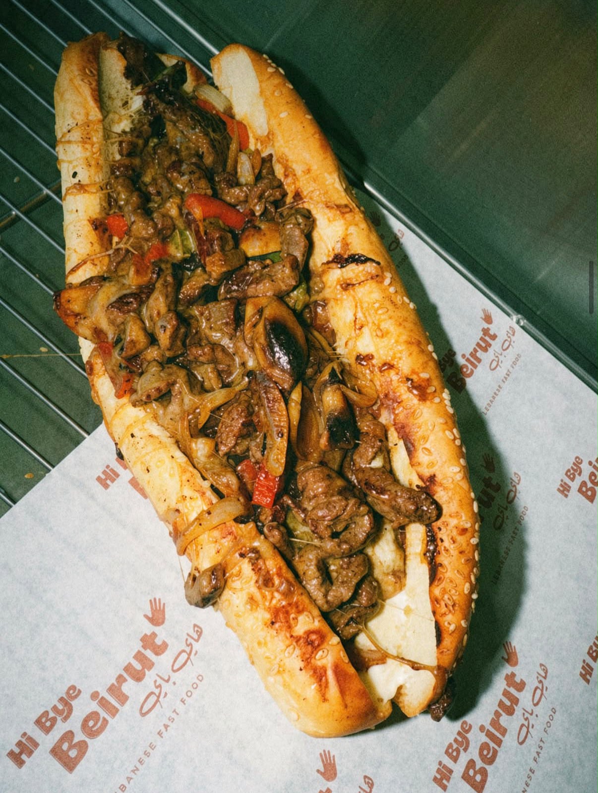 Sandwich sub garni de viande, poivrons et oignons sur papier kraft Hi Bye Beirut