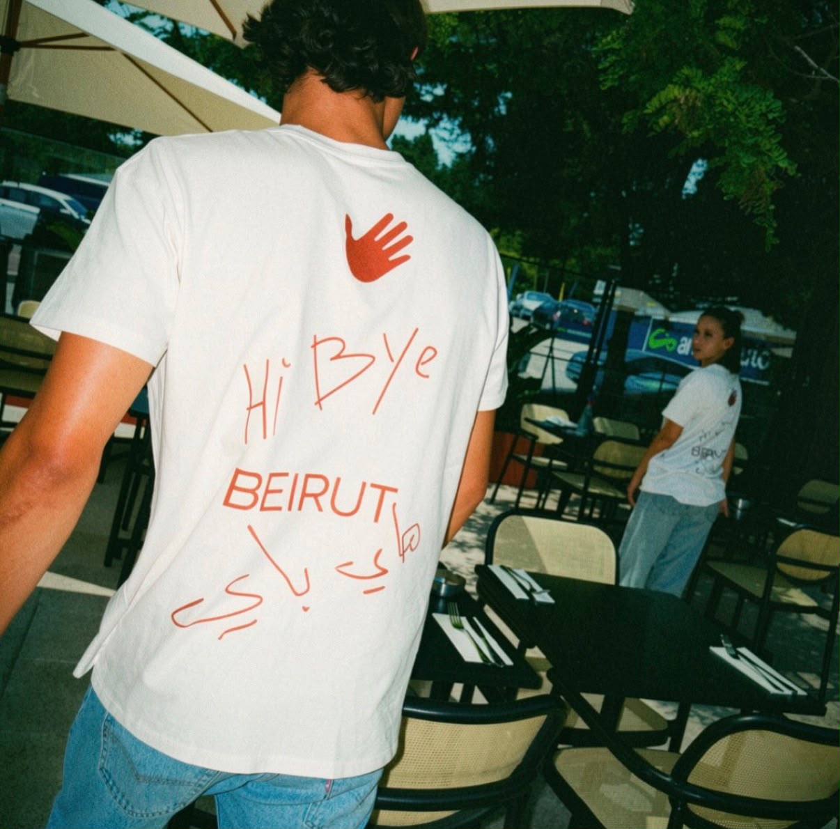 Terrasse ombragée du restaurant avec un client en t-shirt Hi Bye Beirut