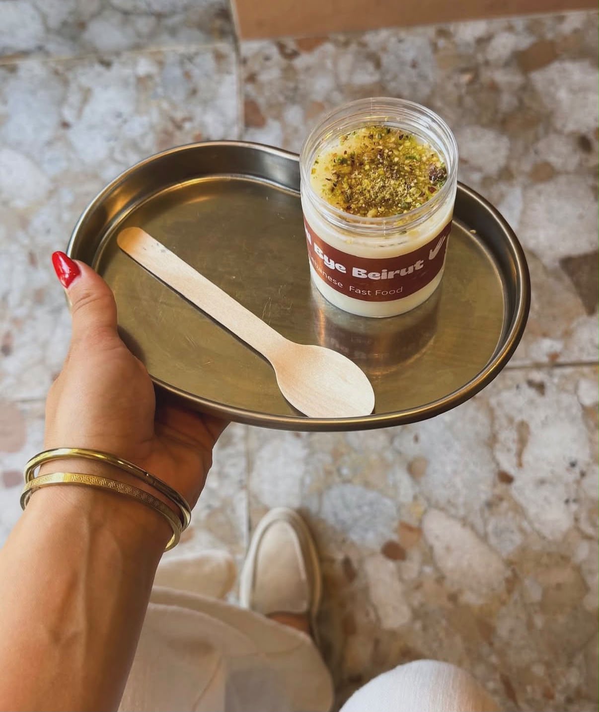 Pot de crème libanaise saupoudrée de pistaches sur un plateau métal